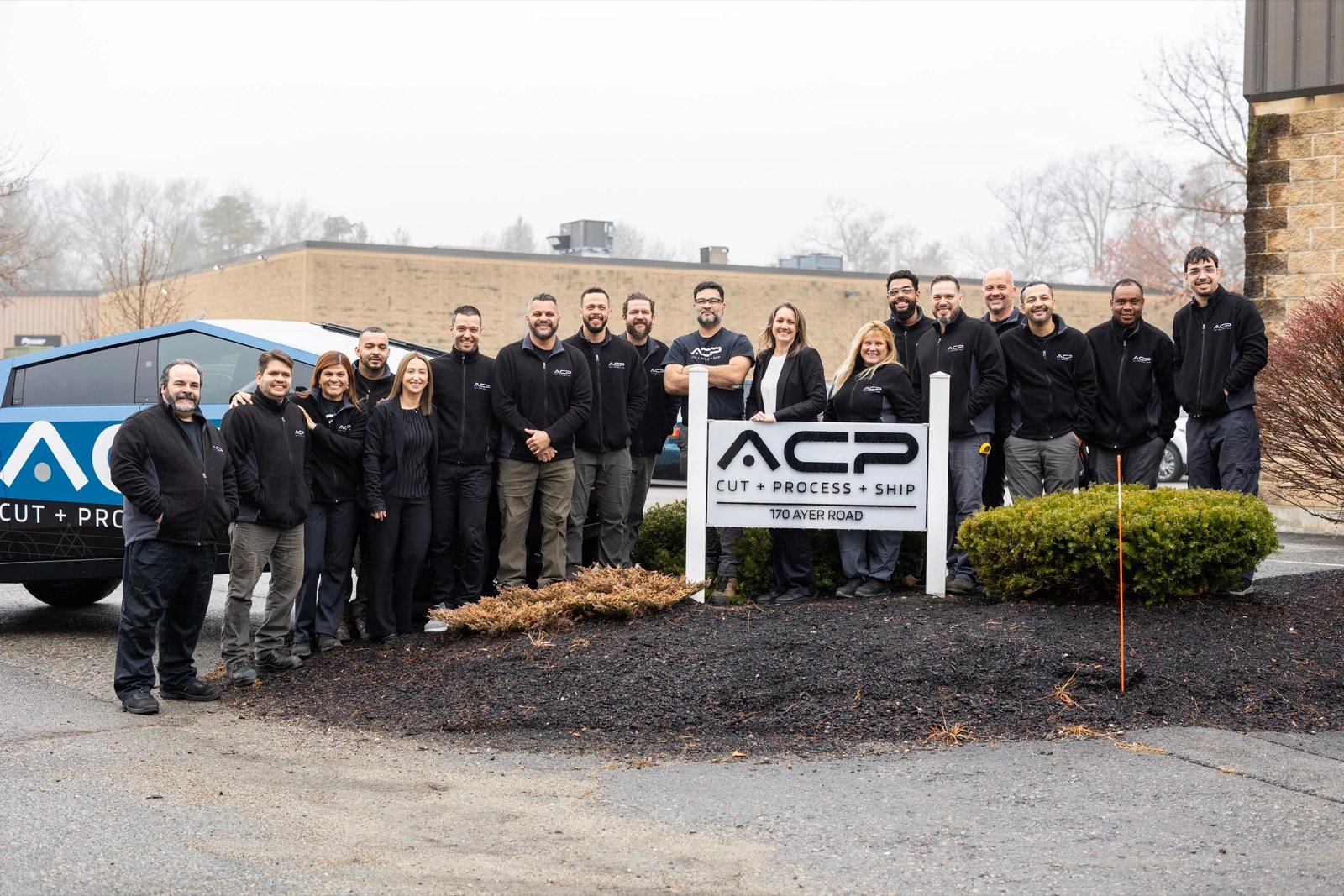 The ACP Waterjet team outside the shop beside the ACP sign at 170 Ayer Road, Littleton, Massachusetts
