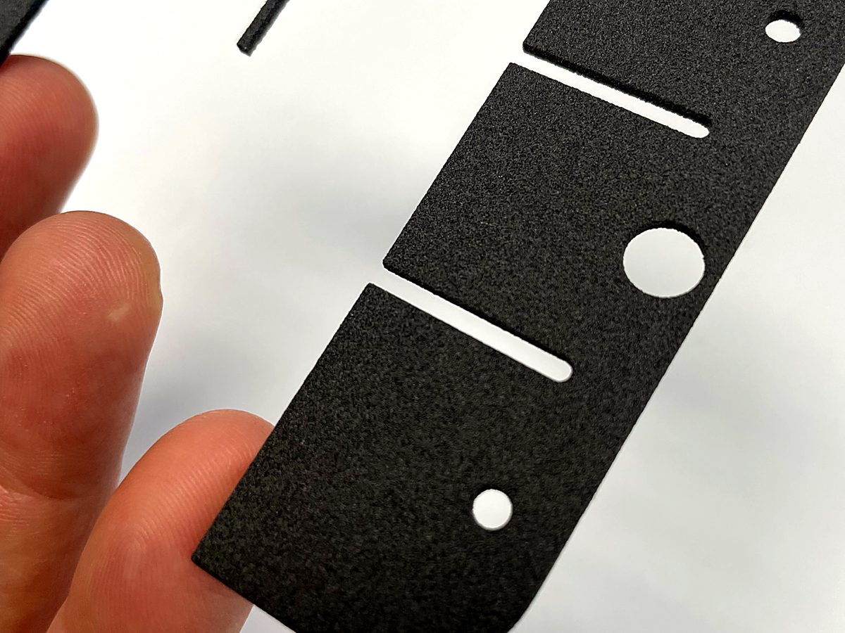 A laser cut black foam sheet with slots at ACP Waterjet