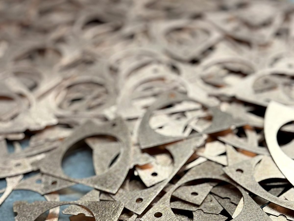 Batch of laser cut steel parts staged for manual deburring at ACP Waterjet