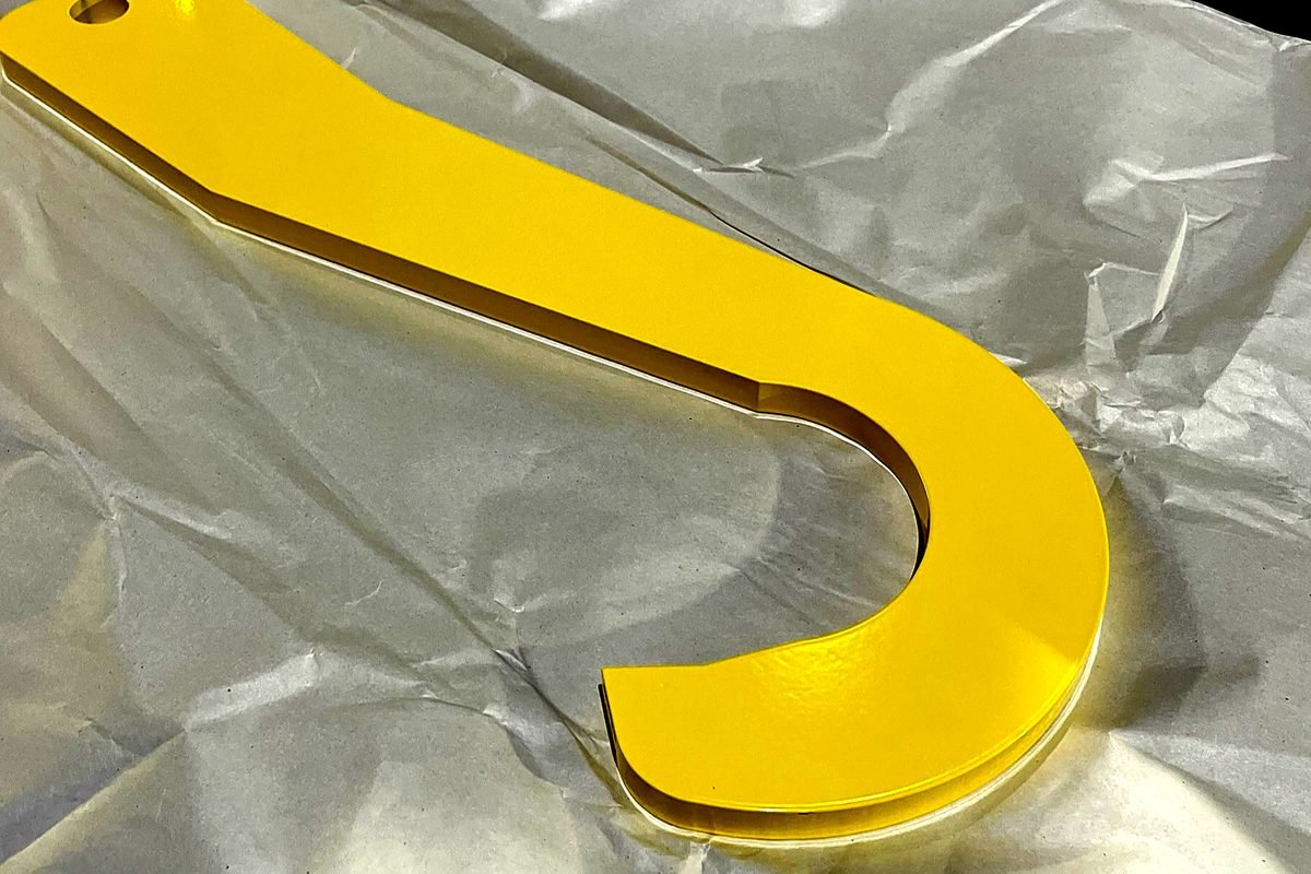 Yellow powder coated steel hook finished through ACP Waterjet in Littleton, MA