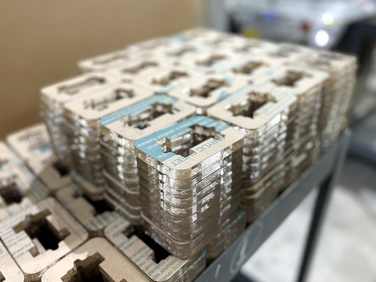 Stacked production run of machined acrylic parts packed at ACP Waterjet