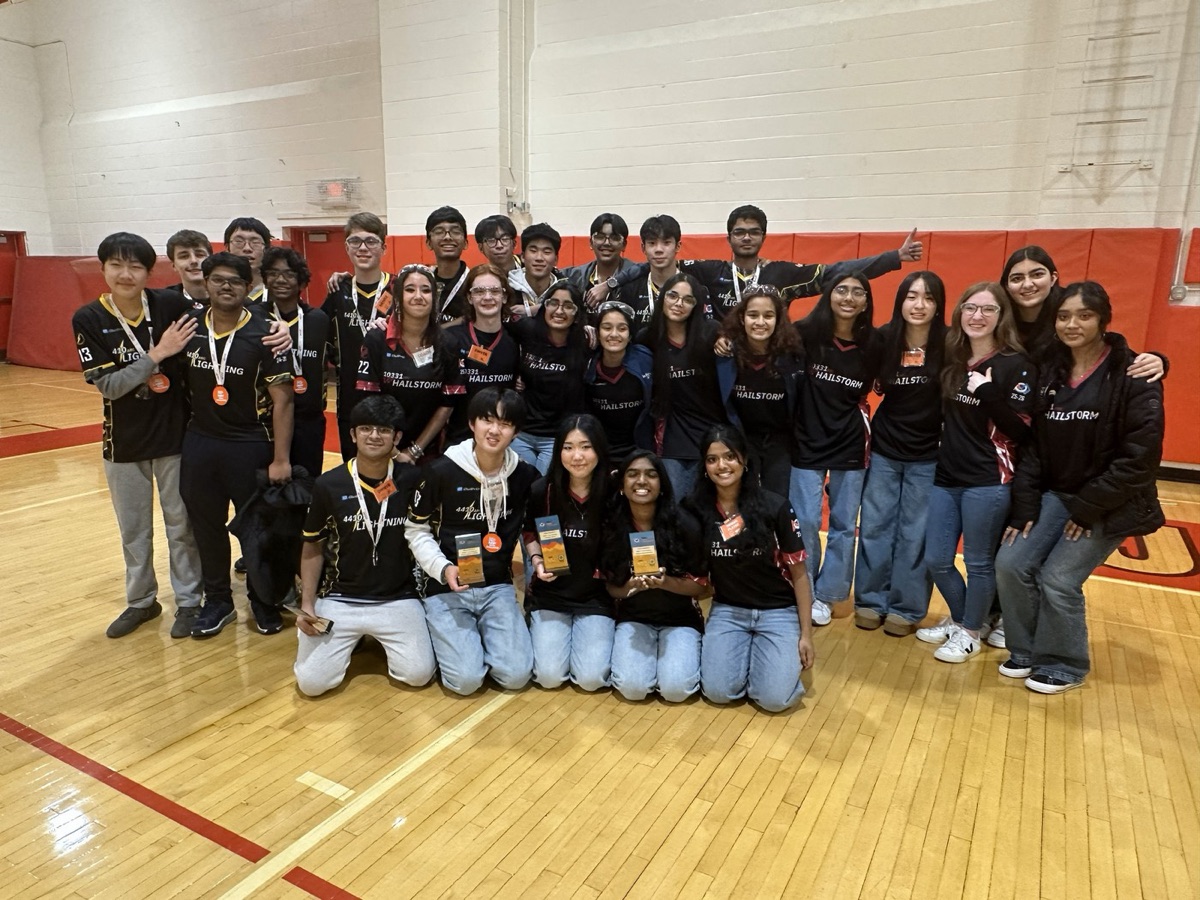Andover Robotics Club students holding trophies and medals on a gym floor