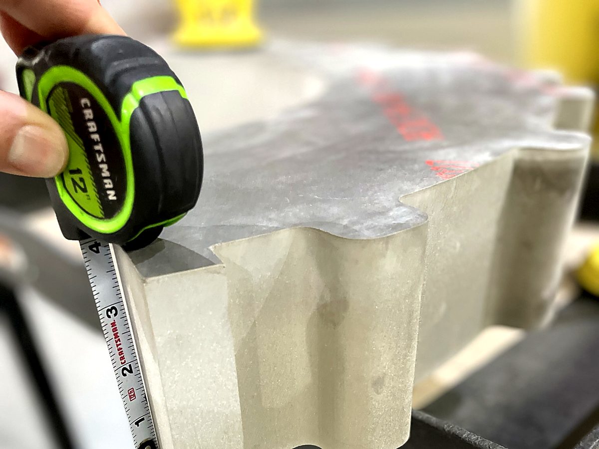 A 4 inch thick waterjet cut part with a tape measure at ACP Waterjet